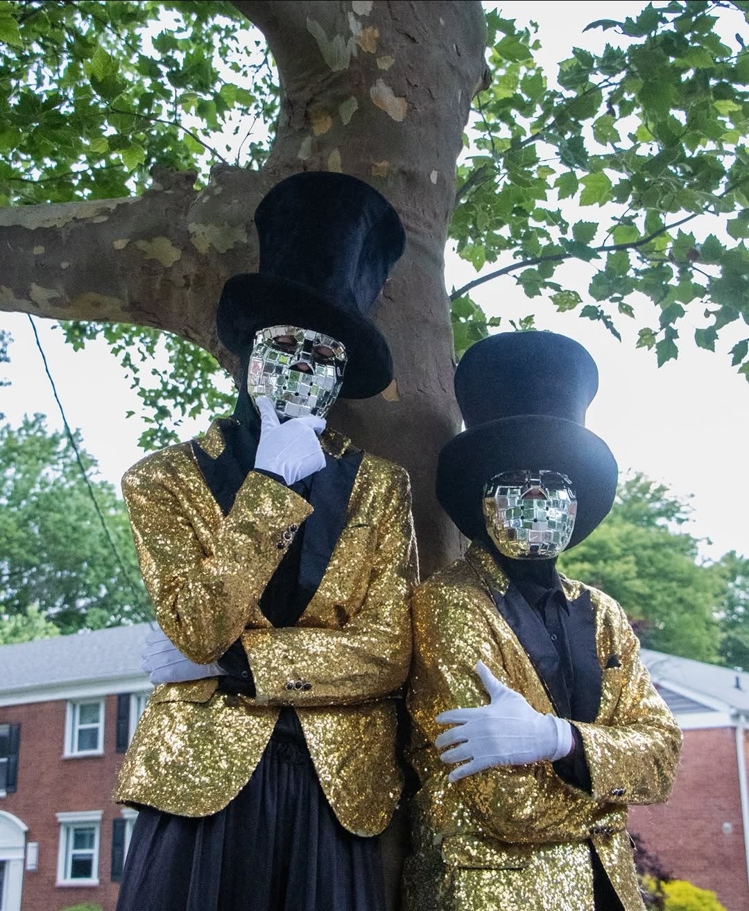 Stilt performers in sequin jackets at an evening event