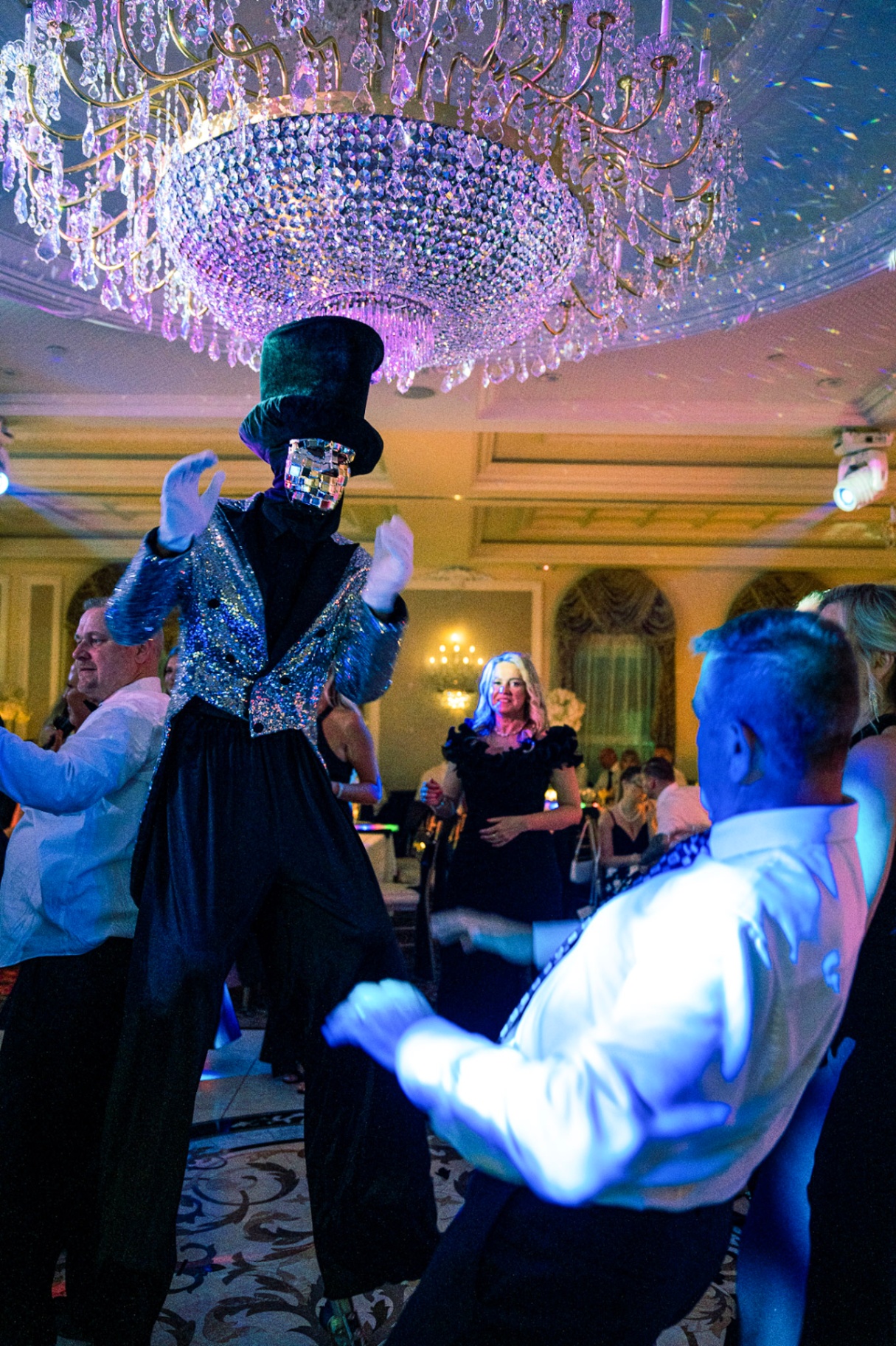 Stilt dancer performing beneath a crystal chandelier at a wedding reception