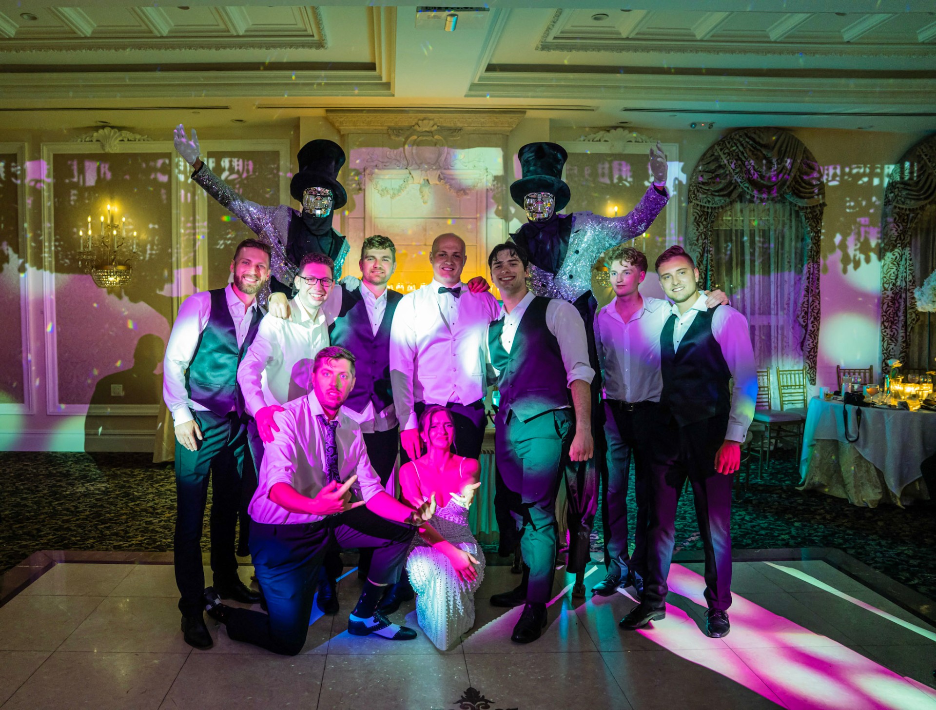 Wedding party posing with two stilt performers on the dance floor