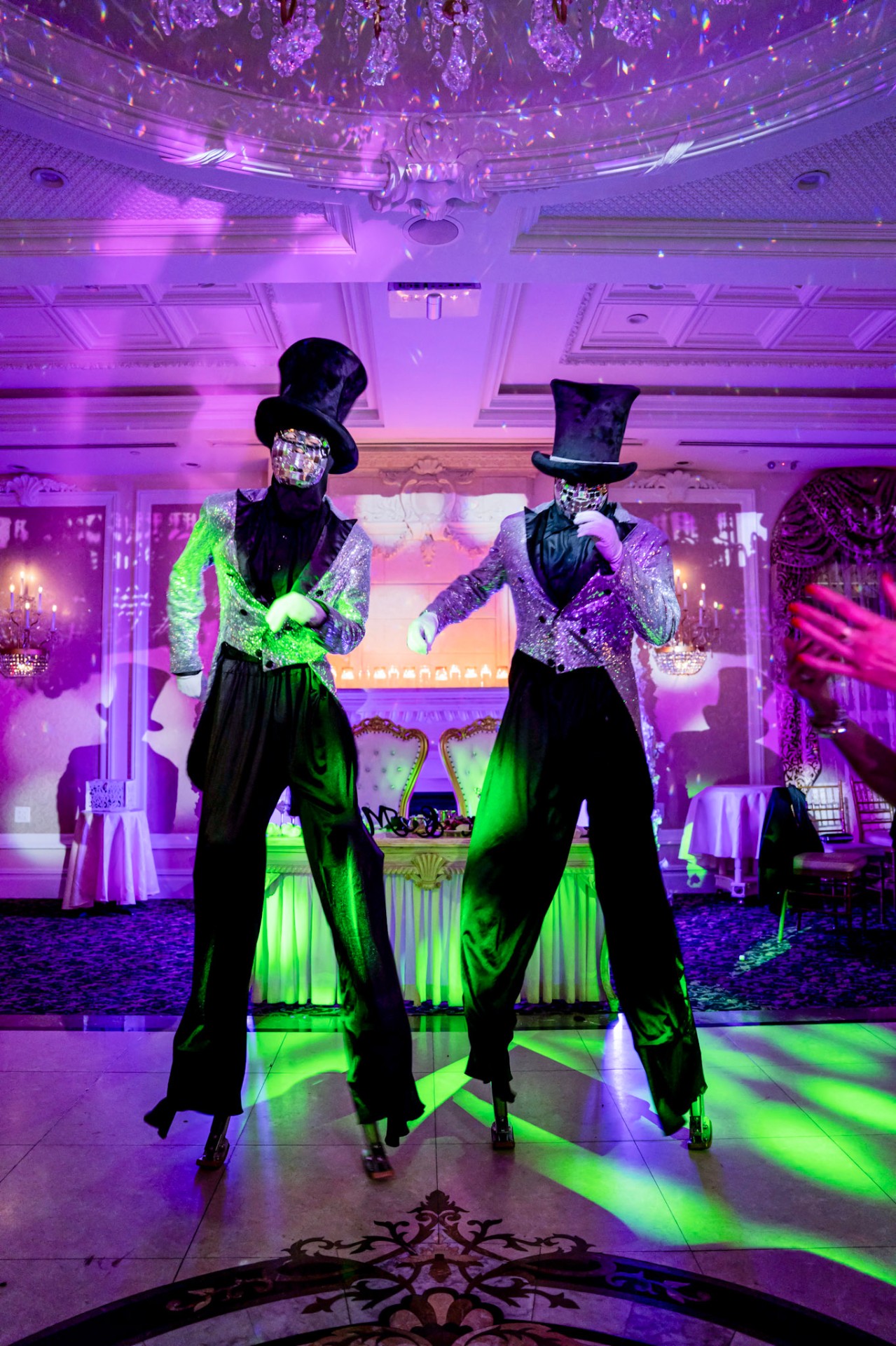 New Hiights stilt dancers in silver sequin jackets performing under stage lights
